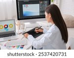 Female graphic designer working with tablet at table in office