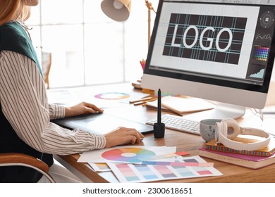 Female graphic designer working with tablet at table in office, closeup