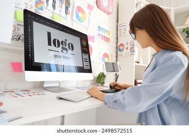 Female graphic designer working with tablet at table in office - Powered by Shutterstock