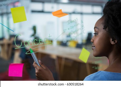 Female graphic designer writing on glass with marker - Shutterstock ID 630518264