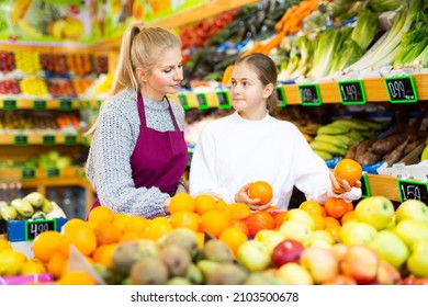 Female Grocery Store Clerk Helps Teenage Girl Pick Ripe Fruits