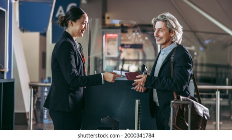 Female ground attendant giving boarding pass and passport to male traveler at airport terminal. Businessman being assisted by flight attendant at international airport. - Powered by Shutterstock