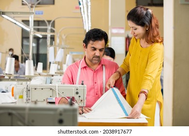 Female Guiding Male Textile Worker Marking On Garment At Factory