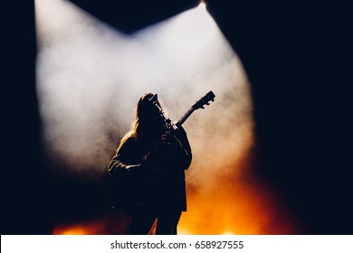 Female guitarist on a stage playing rock on acoustic guitar in a colorful backlights - Powered by Shutterstock