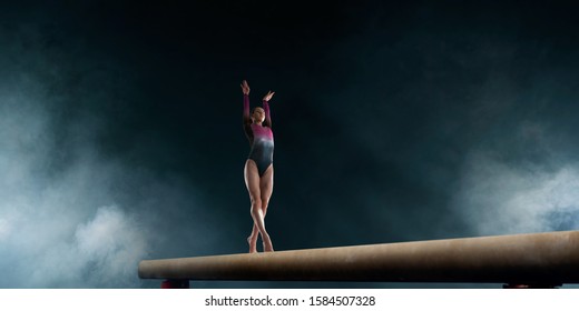 Female gymnast doing a complicated trick on gymnastics balance beam. - Powered by Shutterstock