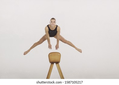 Female gymnast vaulting the pommel horse, front view