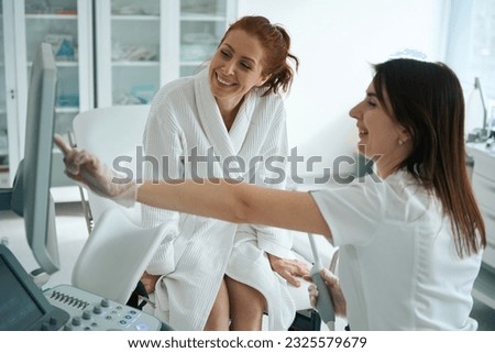 Female gynecologist showing to female patient ultrasound image on screen