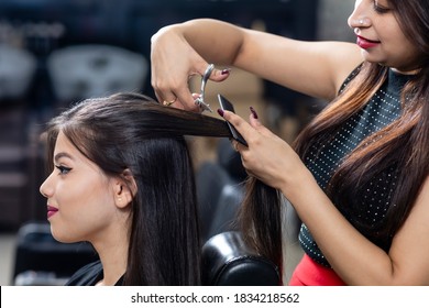 Female hairdresser standing and cutting hair of a cute lovely young woman in beauty salon, beauty salon concept.