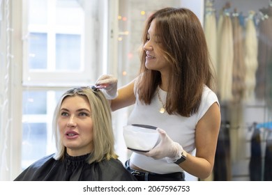 female hairdresser, stylist, colorist dyeing hair for adult customer woman, making mask for growth, nourishment, strengthening - Powered by Shutterstock