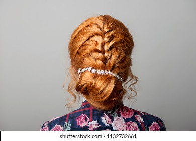 A Female Hairstyle Is A Low Bun On A Red-haired Girl Back View On A Gray Isolate.