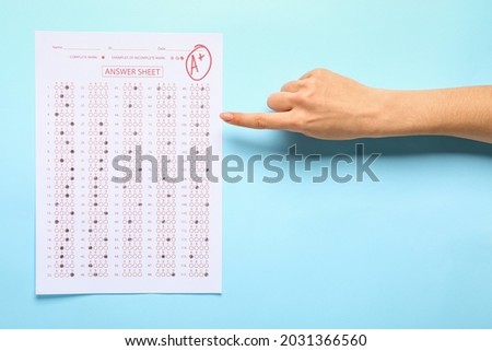 Female hand with answer sheet form on color background
