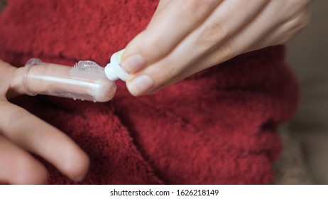 Female Hand Applies Gum Gel On Massager Toothbrush. Teething Concept.