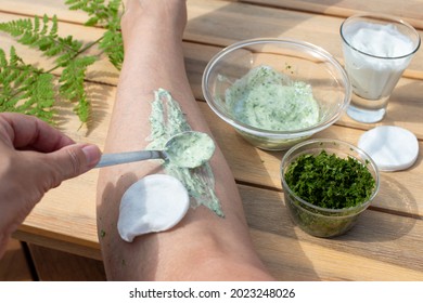 Female hand applying healing cream with Wood Fern leaves and yogurt on her leg. Traditional remedy for varicose veins. Folk medicine.