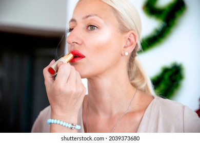 Female hand applying red lisptick on blonde Woman lips, preparing makeup for glamour event - Powered by Shutterstock