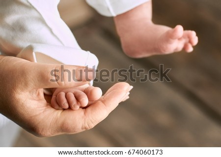 Female hand and baby foot. Leg of child close up.