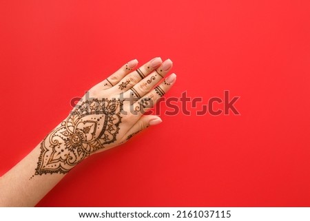 Female hand with beautiful henna tattoo on color background