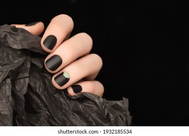 Female Hand With Black Nail Design. Black Nail Polish Manicure. Woman Hand Hold Wrinked Paper On Black Background