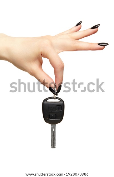 A female hand with a black nails manicure\
holds a black car key with her fingers. Car sharing concept.\
Isolated on white background.