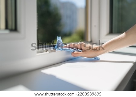 female hand with blue rag washing opened window and plastic frame at office, cleaning service or advertising concept