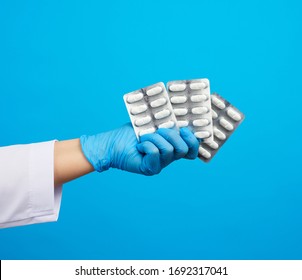 female hand with blue sterile gloves holds a pills in a blister, concept for drug treatment of diseases, blue background