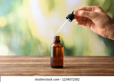 Female hand and bottle with eucalyptus essential oil on blurred background
