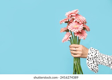 Female hand with bouquet of pink gerbera flowers on blue background - Powered by Shutterstock