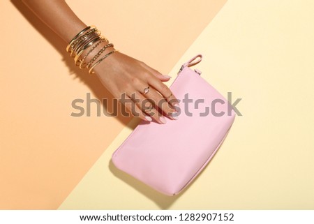 Female hand with bracelets and handbag on colorful background