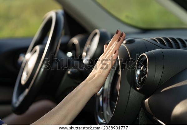 Female hand checking air conditioning panel\
inside car. Woman driver suffer from heat in vehicle holding hand\
at conditioning system cooling grid. Hot summer season and driving\
automobile concept