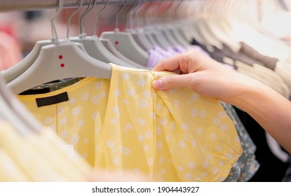 Female Hand Choosing Clothes For Checked Pattern Cotton Dress On The Rack In Cloth Shop At Department Store. Check Price, Discount And Promotion Of Clothing Product.