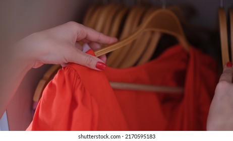 Female Hand Choosing Red Dress On Hanger Closet Closeup