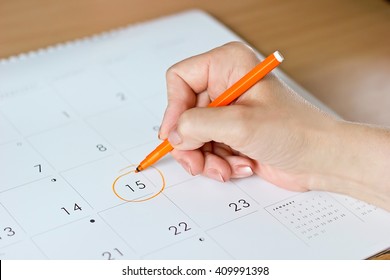 A female hand circling the date of the 15th day in the calendar - Powered by Shutterstock