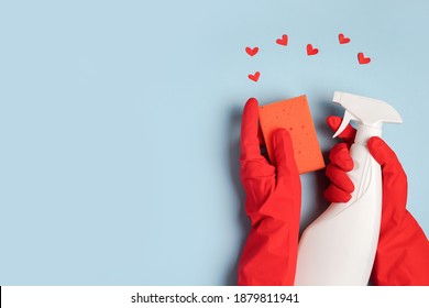 Female hand with cleaning products and red hearts on blue background. Cleaning or housekeeping with love. Copy space. Flat lay, Top view.