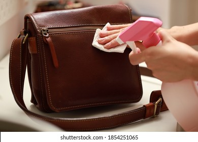 Female hand cleaning the surface of the leather bag. Coronavirus prevention, hygiene to stop spreading coronavirus.