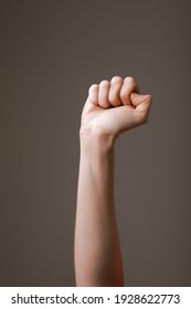female hand clenched into a fist on a gray background. gesture of fighting, winning or protest. Human hand gesturing sign isolated. Female raised arm presenting popular gesture. copy space. - Shutterstock ID 1928622773