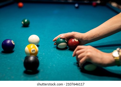 female hand collects colour balls after playing billiards and prepares a new game. spend free time