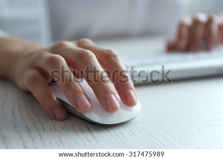 Female hand with computer mouse on table, closeup