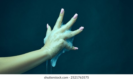 Female hand covered in slime, gesturing against cyan green background. Sci-fi horror movie poster designs, Halloween-themed template. Concept of Halloween holiday. Copy space for ad - Powered by Shutterstock