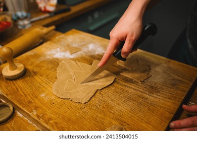 Female hand cut gingerbread dough with a sharp knife at kitchen. Traditional Christmas home bakery. Baking, cooking and christmas concept . High quality photo