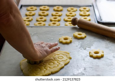 female hand cutting biscuits from the dough in flower shape