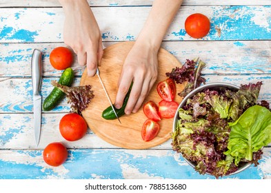 Female Hand Cutting Cucumber And Making Salad. Top View.