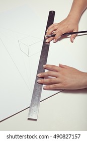 Female Hand Drawing A Cube With Pen And Ruler In Two Point Perspective