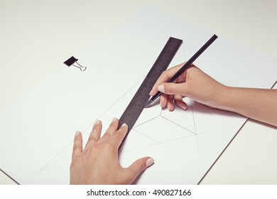 Female Hand Drawing A Cube With Pen And Ruler In Two Point Perspective