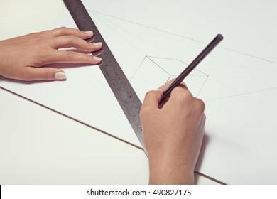 Female Hand Drawing A Cube With Pen And Ruler In Two Point Perspective