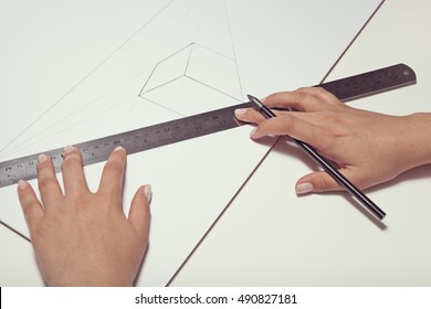 Female Hand Drawing A Cube With Pen And Ruler In Two Point Perspective