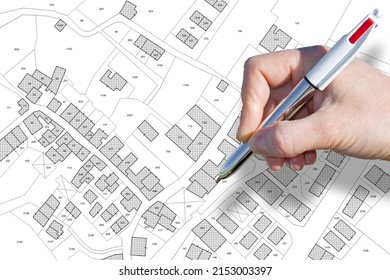 Female hand drawing an imaginary cadastral map of territory with buildings, roads and land parcel - land and property registry and real estate property concept - Shutterstock ID 2153003397