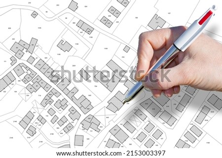 Female hand drawing an imaginary cadastral map of territory with buildings, roads and land parcel - land and property registry and real estate property concept