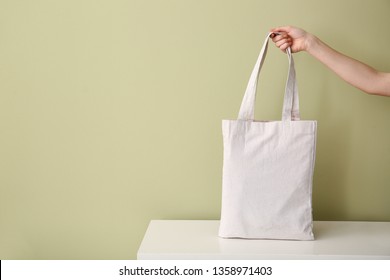 Female hand with eco bag on table against color background - Powered by Shutterstock