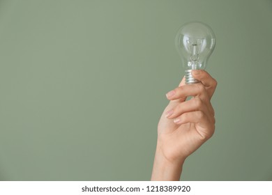 Female hand with eco light bulb on color background - Shutterstock ID 1218389920