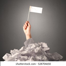 Female Hand Emerging From Crumpled Paper Pile Holding A White Blank Flag 