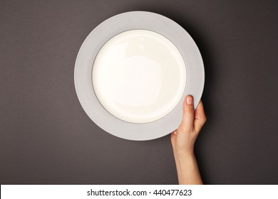 Female Hand And Empty Plate On Dark Background